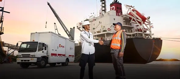 apreton de manos de dos hombres y atras barco y camion