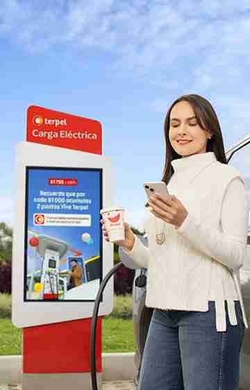 mujer viendo celular en estacion de carga electrica